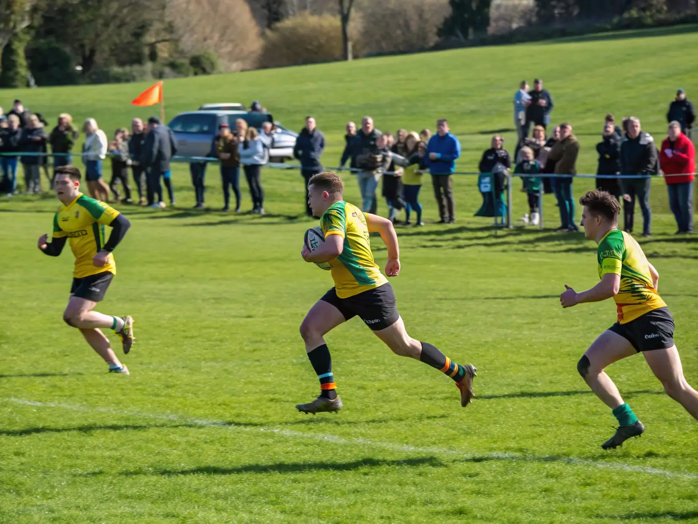 A dynamic image of a community rugby match, showcasing players in action, with spectators cheering from the sidelines, highlighting the excitement and camaraderie of the event.