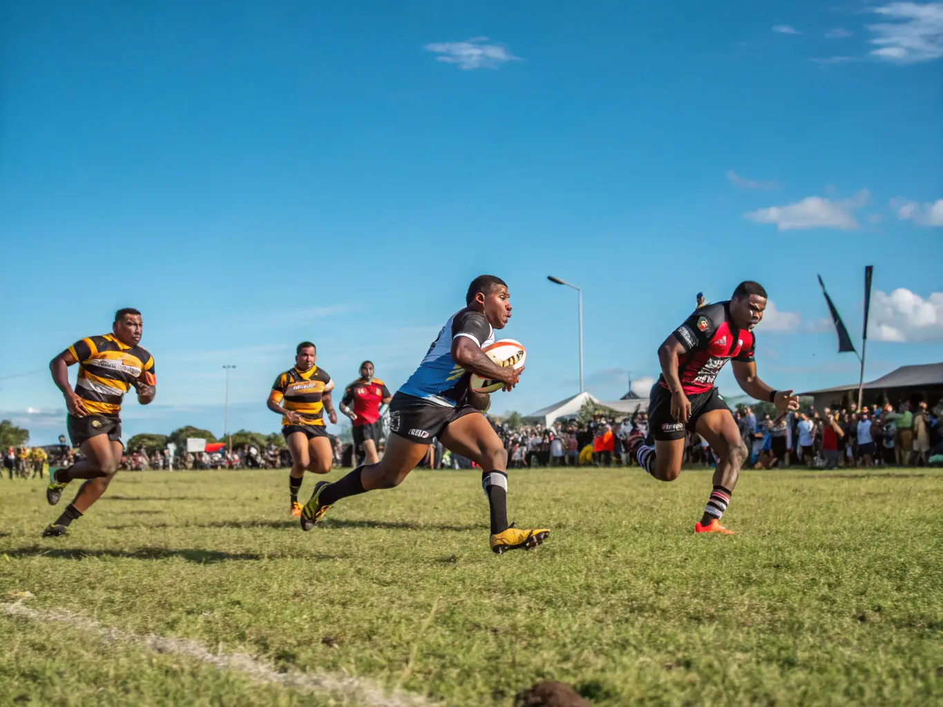 A lively rugby match with players in action, cheering crowds, and team huddles on the field. The atmosphere is electric, showcasing the excitement of community rugby tournaments.